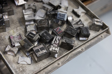 Vintage lead letterpress printing blocks against a weathered metal drawer background with bokeh.