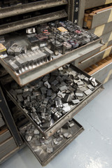Vintage lead letterpress printing blocks against a weathered metal drawer background with bokeh.