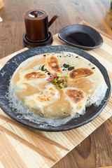 Chicken Gyoza, japanese pan fried dumplings served on a rustic plate.