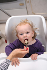 Fototapeta premium Mother feeds baby boy with a spoon porridge