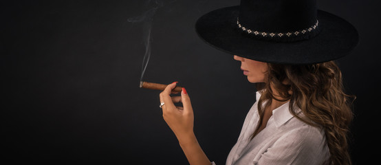 Portrait of sexy elegant lady with hat smoking cigar