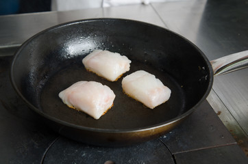 Pan fried golden fish fillet cubes, frying in real butter, in a non stick rustic pan.