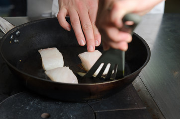 Pan fried golden fish fillet cubes, frying in real butter, in a non stick rustic pan.