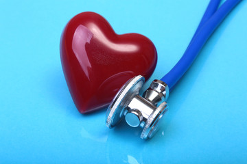 medical stethoscope and red heart on blue mirror background. selective focus.