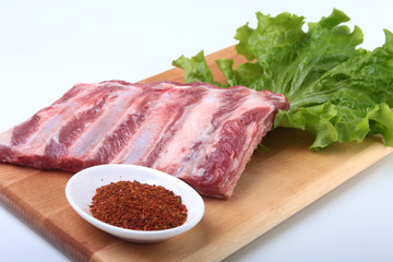 Fototapeta premium Raw pork ribs with herbs and spices on wooden board. Ready for cooking.