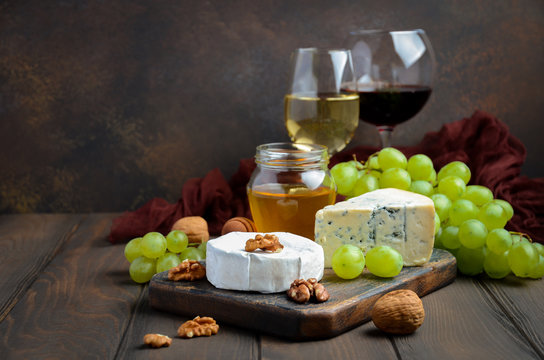 Variety of cheese with grapes, walnuts and wine. Selective focus, copy space.