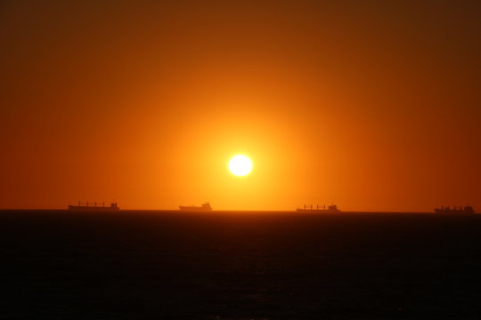 Container ships in front of Fremantle, sunset in Indian Ocean view from Cottesloe Beach, Western Australia 
