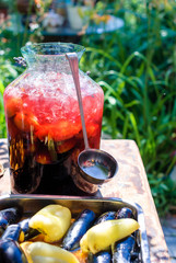 A large bottle of cold sangria with a ladle on the dacha table