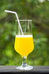 Freshly made pineapple juice in tall glass with straw outdoors 