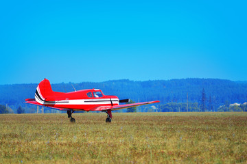 Fototapeta na wymiar A small red plane landed on the field
