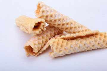 Homemade wafer rolls with powdered sugar isolated on white background