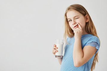 A shot of an adorable blonde girl with a glass of milk. Healthy teeth are important.