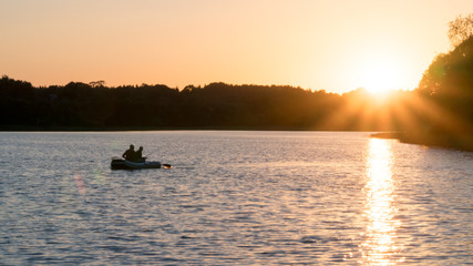 beautiful sunset on the lake, fishermen on the boat.