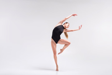 Serious young woman performing element of gymnastics choreography - obrazy, fototapety, plakaty