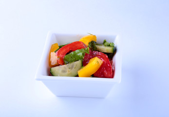 fresh vegetable salad with tomato, cucumber, bell pepper and lettuce leaf in white bowl.