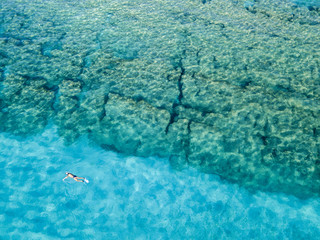 Vista aerea di scogli sul mare. Panoramica del fondo marino visto dall’alto, acqua trasparente. Nuotatori, bagnanti che galleggiano sull’acqua. Snorkeling e immersioni
