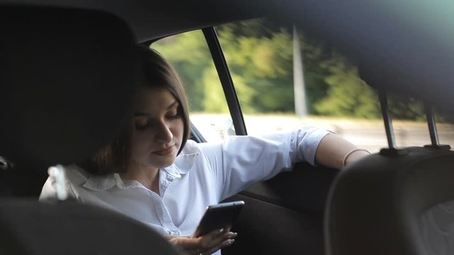 Wonderful business girl rides in a taxi and to use the phone