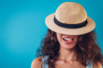 Portrait of a pretty woman hiding under hat and showing tongue