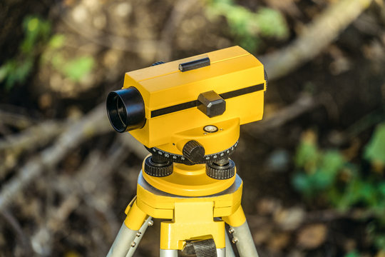 Yellow geodetic optical level on a tripod. Construction engineering equipment.