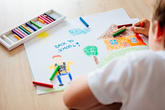 Child drawing picture of boy going to school.