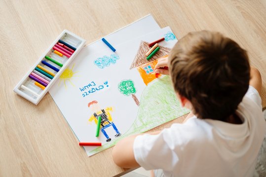Child drawing picture of boy going to school.