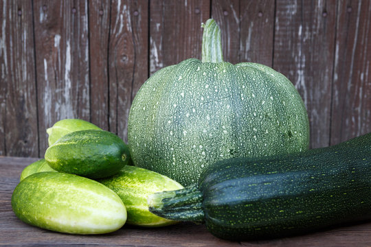 Fresh zucchini and cucumbers on the wooden table. Bio vegetables on a wooden background.