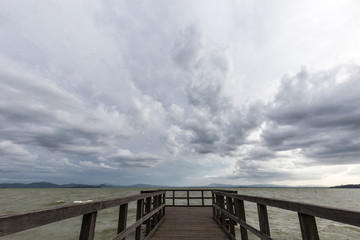 Geometric, first person view of a pier on a lake, beneath an overcast, moody sky