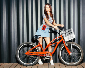 Plakat Loker long legged girl asian in a summer outfit, sneakers, cassette player and headphones posing with a vintage red bicycle. Night shot. Outdoor.