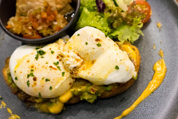 Mexican on toast sandwich with fried egg, cucumber, tomatoes, and vegetable salad