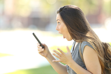 Profile of an amazed woman using a phone