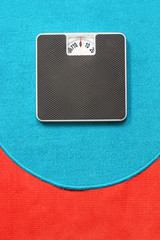 Bathroom scale on blue and red carpet. Background for leaflets and web sites on slimming and dieting theme.