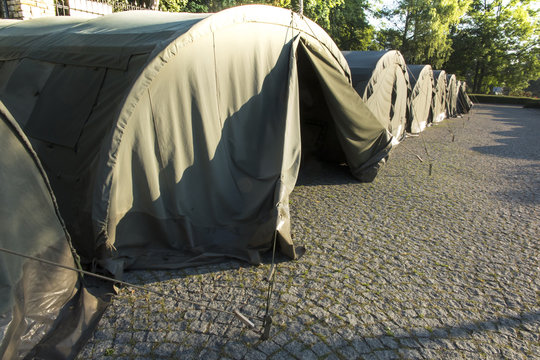 several large military tents on the paved area