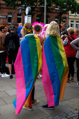 Pride Parade in Hamburg; lesbian girls couple with colorful flags on the back