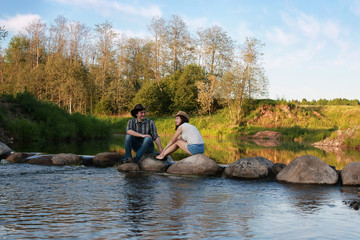 couple of young people admire the sunset in the spring evening on the river