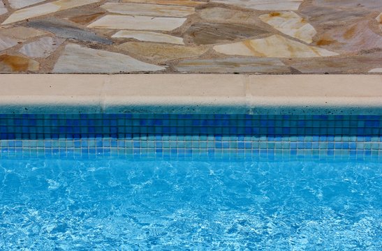 Pool side with blue tiles and clear water