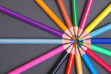 Fototapeta premium Bright colored pencils are made of wood laid out in the form of rays. Colored pencils on black background