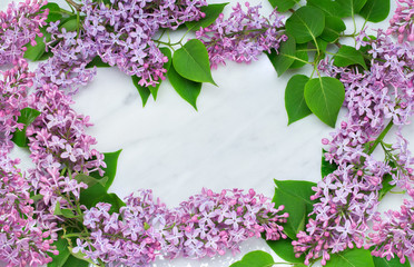 Lilac blossom branches frame on Carrara marble countertop