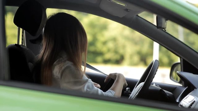 Cute girl talking on the phone behind the wheel of the car