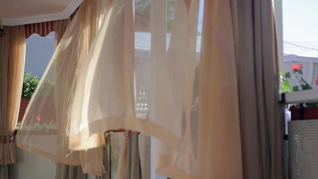Beige curtains in bower are fluttering on the light breeze wind. Sunny afternoon. Changing focus from background to first plan. Steady. Medium.
