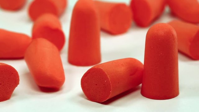 Red ear plugs on white background, soft polyurethane foam. Earplugs offer hearing protection against harmful noise