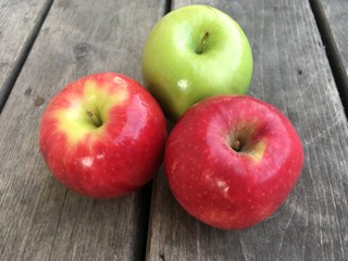 Group of three apples on a wood table top