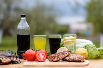 Chicken breast grilled on a wooden Board. Food photography chicken chili steak on the background with vegetables and black soda and lemonade. Food and summer drinks for a picnic in the fresh air.