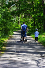 Fototapeta premium Grandfather and grandson ride a bicycle in the city park. May 28, 2017.