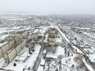 Sprinkled with snow grain elevator. Winter view of the old Soviet elevator. Winter view from the bird's eye view of the village. The streets are covered with snow