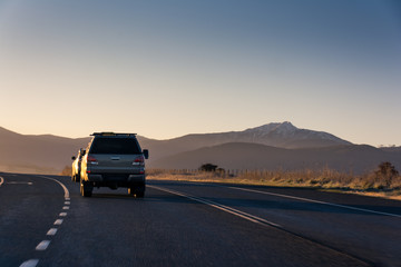 Country highway with cars leading towards mountains at sunrise - 166933716