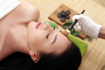 Obraz na płótnie Canvas Spa massage for woman with facial mask on face