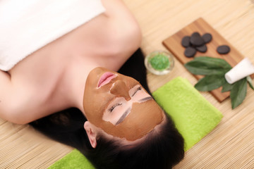 Obraz na płótnie Canvas Girl with facial mask lying in beauty health spa center