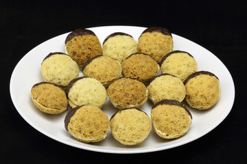 Homemade Christmas cookies, special Czech sweets on plate, isolated on black. Pastry, cookies, biscuit with spice (cinnamon) and nuts (walnuts) like tea biscuits, half dipped in chocolate