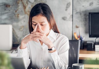 Frustrated Asian businesswoman cover her face with two hand and feel upset from work in front of laptop computer on desk at office,Stress office lifestyle concept.