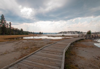 Fototapeta premium Curved Boardwalk next to Tangled Creek and Black Warrior Springs leading into Hot Lake in the Lower Geyser Basin in Yellowstone National Park in Wyoming United States